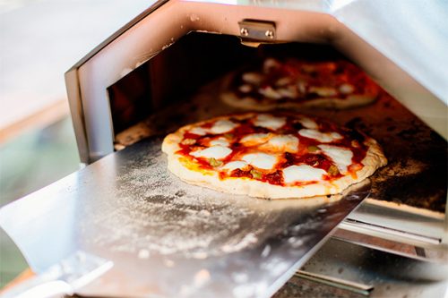 taking a pizza out of a pizza oven