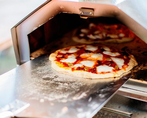 taking a pizza out of a pizza oven