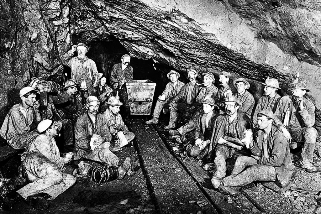 historic image of cornish tin miners eating pasties underground