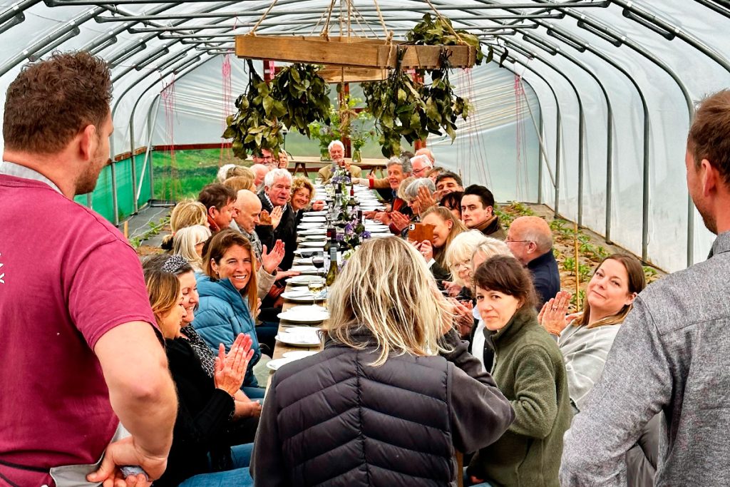 garden supper srved on a long table laid in a polytunnel at roseland market garden for the roseland festival