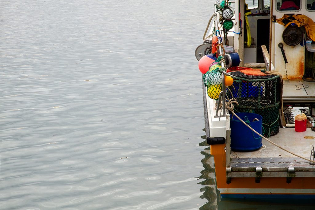 fishing boat in hgarbour with colourful buoys hanging over the side