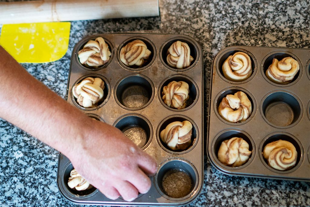 loading a muffin tray with cinnamon twists ready to bake